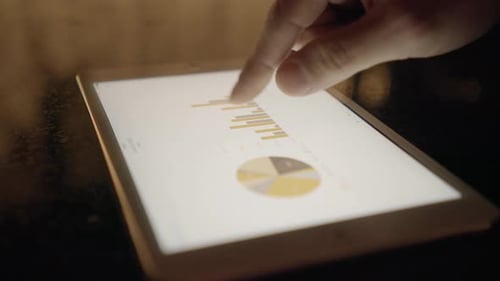 Scrolling Through Data Charts on a Glowing Tablet
