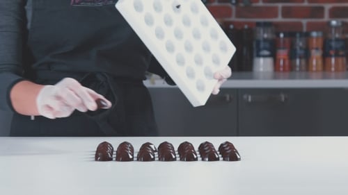 Conditor Chocolatiers prüft fertige Pralinen.