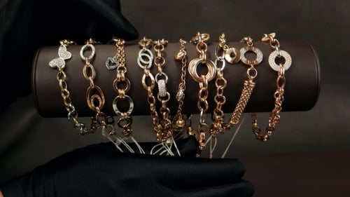 Schmuck im Laden, eine Demonstration goldener Ornamente, Hand in einem schwarzen Handschuh, gelbe Armreifen