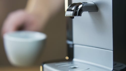 Junger Mann stellt eine Tasse in die Kaffeemaschine