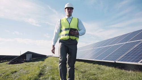 Man In Vest Walking Near Solar Panels