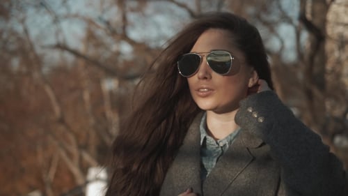 Woman In Coat And Sunglasses In Autumn Park. Student Girl Walking In Glasses And Posing.