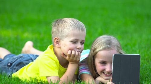 Children Watching Tablet Device on Grass in Summer