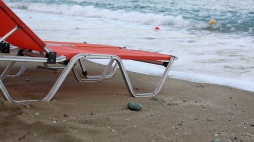 Empty Sunbeds Standing On a Beach By a Blue Sea