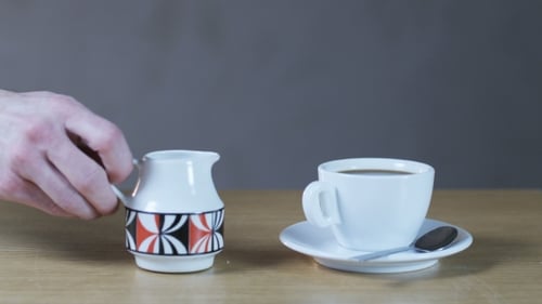 Ein Mann gibt Sahne in eine Kaffeetasse