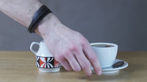 Ein Mann rührt sich mit einem Teelöffel in eine Tasse