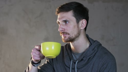 Young Man Drinks Tea From A Green Cup