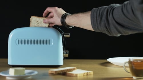 Man Puts Two Loaves Of Bread Into An Electric Toaster