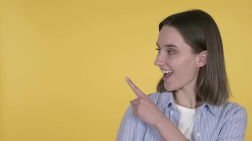 Young Woman Points to Side with Happy Expression