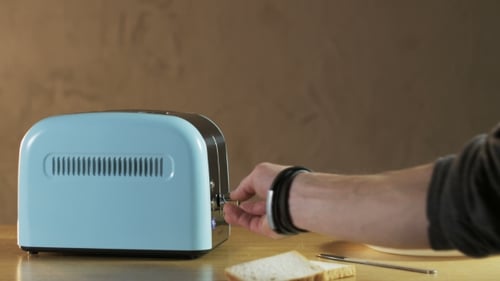 Hand Toasts Bread in a Blue Toaster