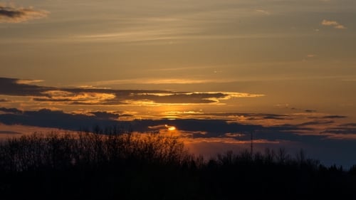 Orange Sun Setting Behind Clouds And Trees