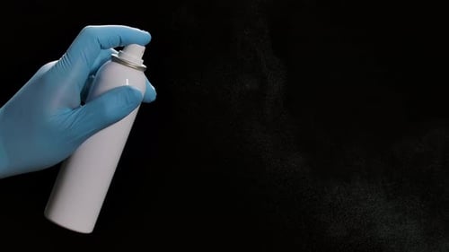Sprühen von Desinfektions-Aerosolspray auf schwarzem Hintergrund. Desinfektionsmittel zur Vorbeugung von Erkältungen