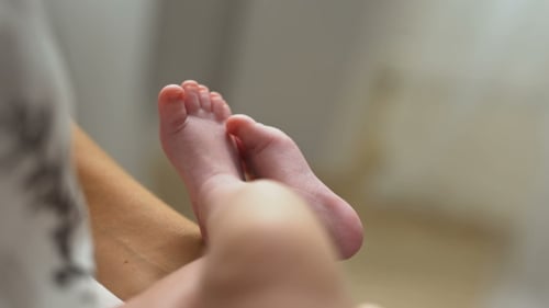 Tiny Infant Feet Held by Adult