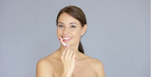 Beautiful Woman Brushing Teeth, Smiling at Camera