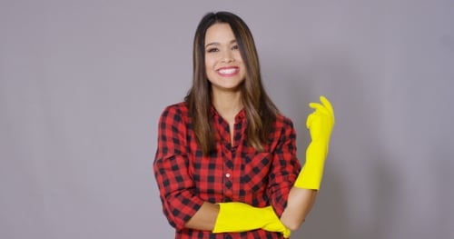 Young Housewife Putting On Rubber Gloves