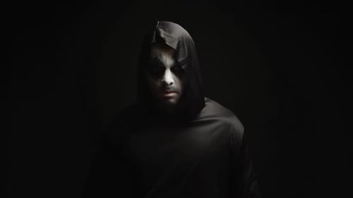 Man in Dark Robe with Face Paint Appears