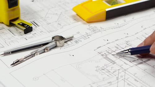 Engineer Sits at the Table, Chooses a Drawing That Is More Optimal for Him. Close Up