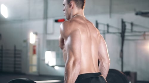 Rear Side View On Man Exercising At Gym