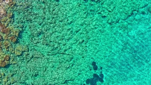 Turquoise Ocean Meets Rocky Shoreline Aerial View