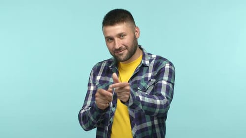 Ein hübscher kaukasischer Mann in Freizeitkleidung lädt Sie ein, mit den Finger zu schnappen und auf die Kamera zu zeigen