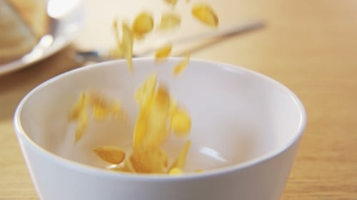 Golden Cornflakes Pouring Into White Bowl