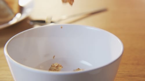 Cereal Pieces Falling into a White Bowl