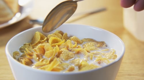 Hand Stirring Corn Flakes in Milk with Spoon