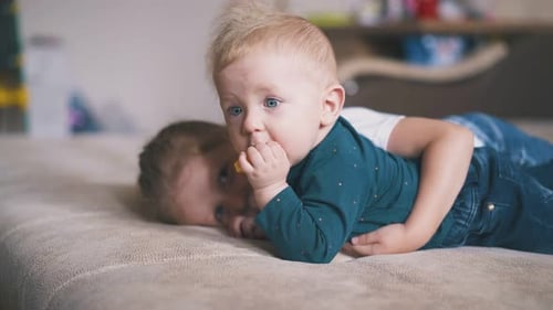 Lovely Girl Hugs Brother Nibbling Yellow Circle on Bed