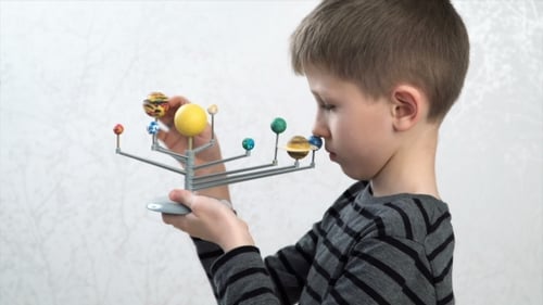 Boy Turning The Models Of Planets