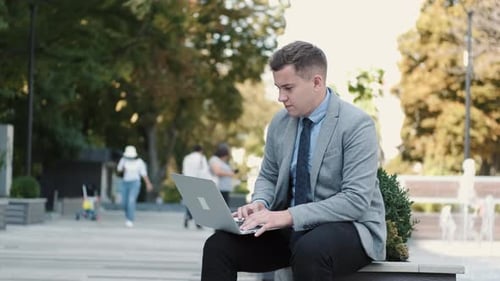 Business Man in Suit Using a Laptop in a Public Park
