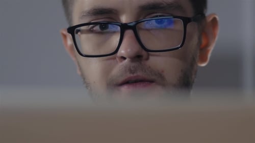 Man In Black Rim Glasses Using His Computer In Office. Businessman With Screen Reflection In The
