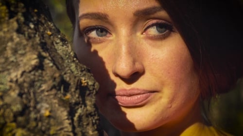 Beautiful Woman Posing by a Tree in Sunlight