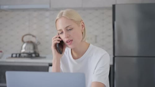 Woman Talking On Mobile Phone Using Laptop Computer