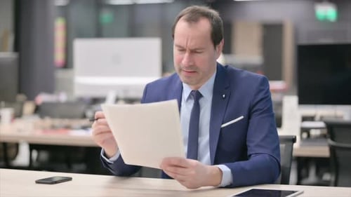 Businessman Upset While Reading Documents in Office