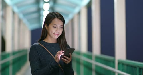 Woman use of mobile phone in city at night