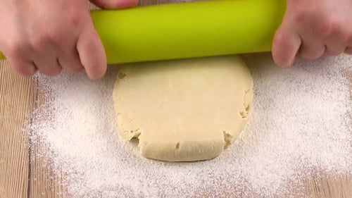 Hands Rolling Dough on Wooden Counter