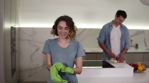 Portrait of Determined Wife Ready to Start Cleaning the Household Puts on Green Gloves and Smiling
