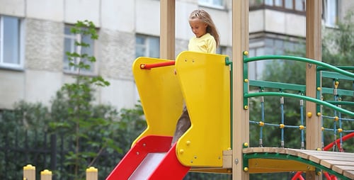 Girl Slides Down Colorful Slide on Playground