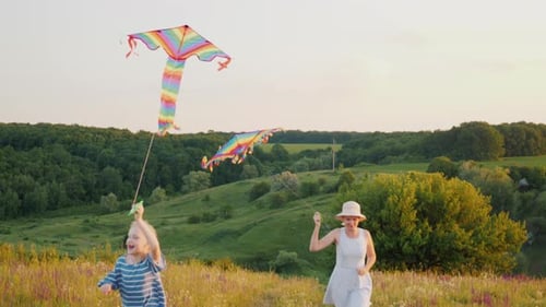 Child and Woman Run with Kites in Meadow