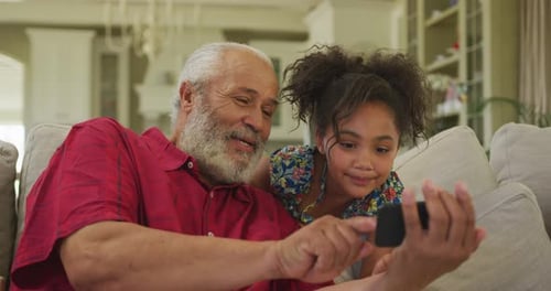 Grandfather and Granddaughter Bonding with Smartphone Indoors