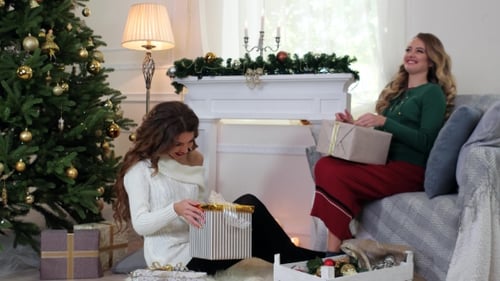 Women Wrapping Christmas Presents Near Fireplace