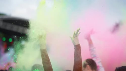 Group of friends holding coloured powder and throwing up at Holi Festival. Shot with RED helium came