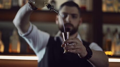 Bartender at the Bar Pours Cocktail Ingredient Into a Measuring Cup Jigger