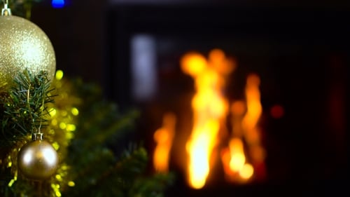 Geschmückter Weihnachtsbaum mit Lichtern vor dem Kamin