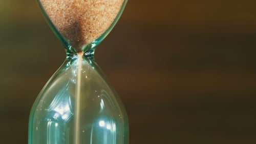Reloj de arena sobre un fondo de madera, la arena cae dentro