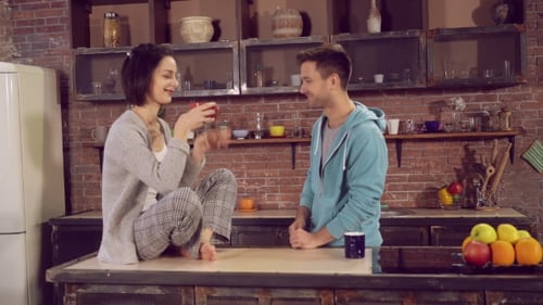 Young Couple Talking and Drinking Coffee in Kitchen