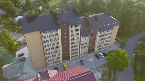 Aerial view of multistory apartment building in green residential area.