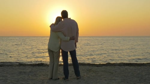 Loving Senior Couple Enjoying Sunset Over Sea