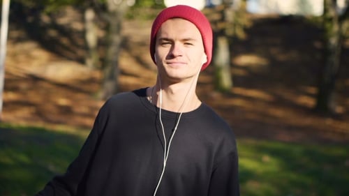 Skateboarder with Red Beanie Walking Through Park