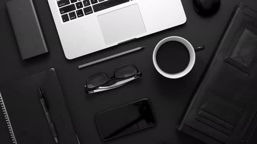 Business Desktop Concept. Mix of Office Supplies and Gadgets on a Black Table Background